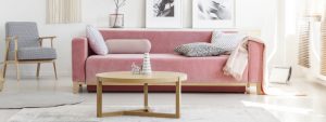 Pink sofa with patterned pillows and wooden coffee table with ar
